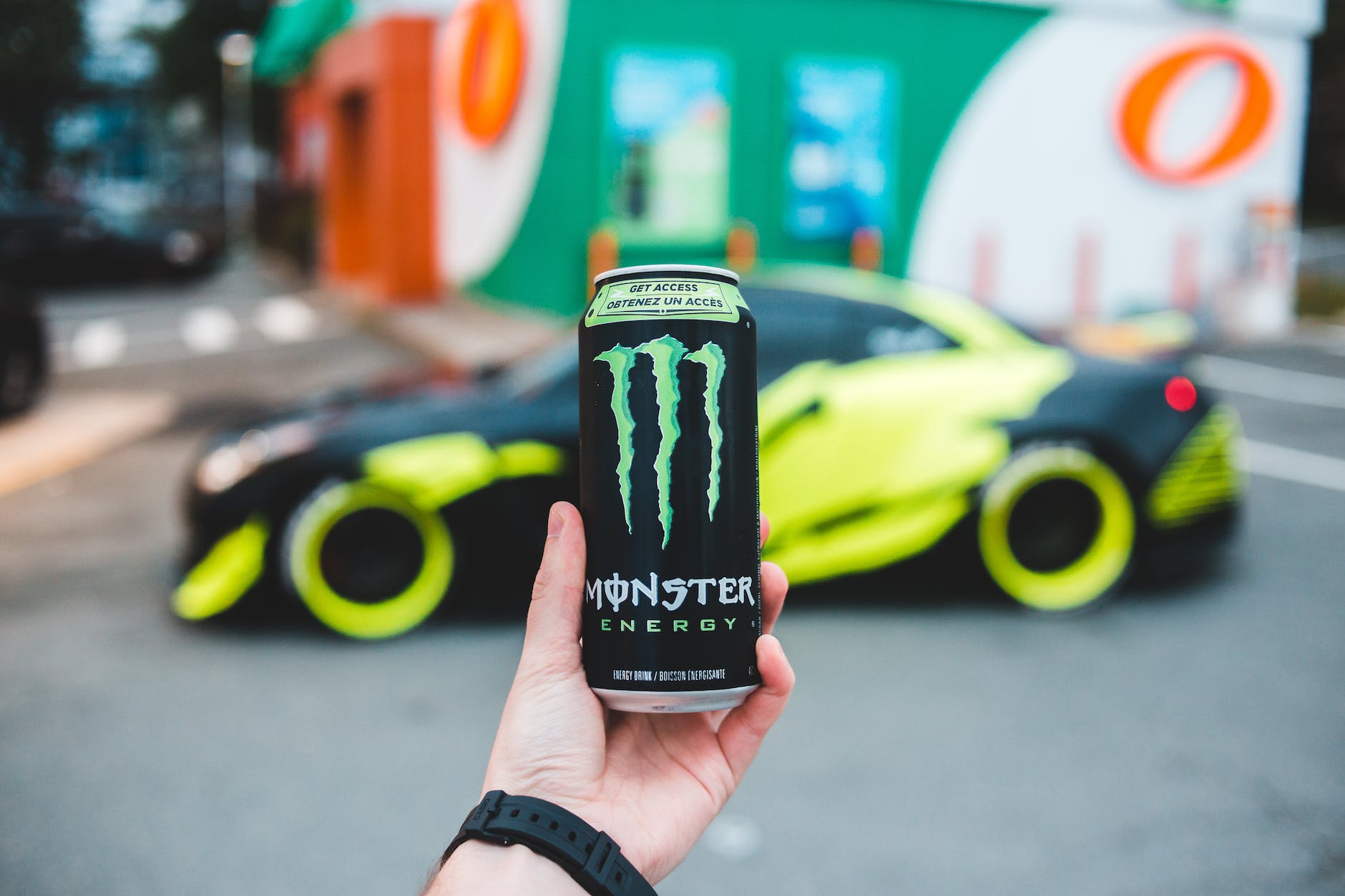 anonymous person with energy drink against car
